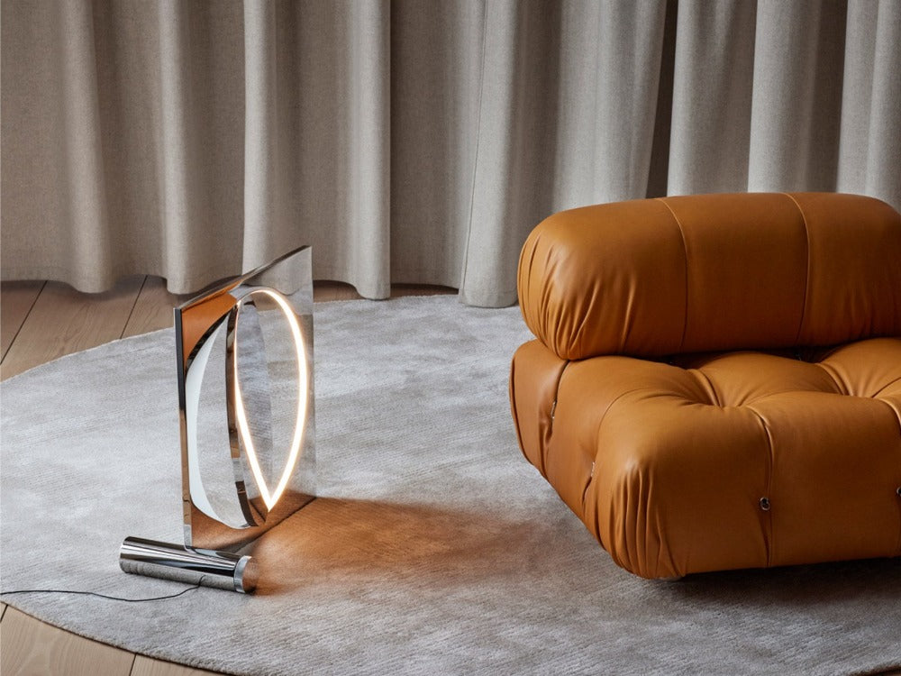 The sculptural Moonsetter floor lamp by Louis Poulsen in chrome-plated aluminum has a rotating disc that allows customization of the reflection of the glare-free light emitted by the LED light source elegantly submerged in the frame. Design by Anne Boysen.