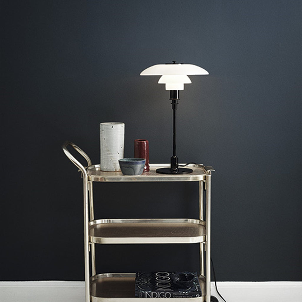 The PH 3/2 Table Light by Paul Henningsen for Louis Poulsen features a reflective three-shade system, which directs the majority of the light downwards. The shades are made of hand-blown opal three-layer glass, which is glossy on top and sandblasted matte on the underside, giving a soft and diffused light distribution.