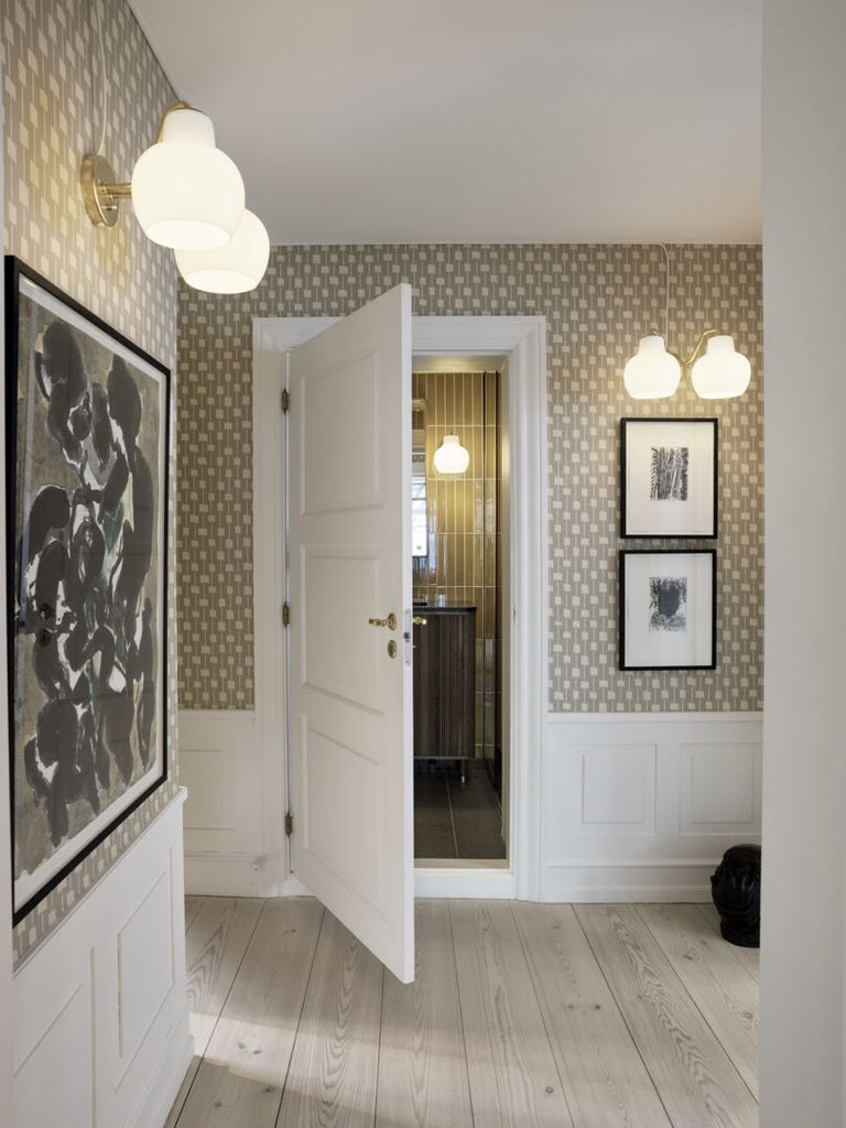 The VL Ring Crown wall sconce by Louis Poulsen has a characteristically organic form that emits light directed primarily downwards, while the opal glass provides a comfortable and uniform illumination of the area around the fixture.