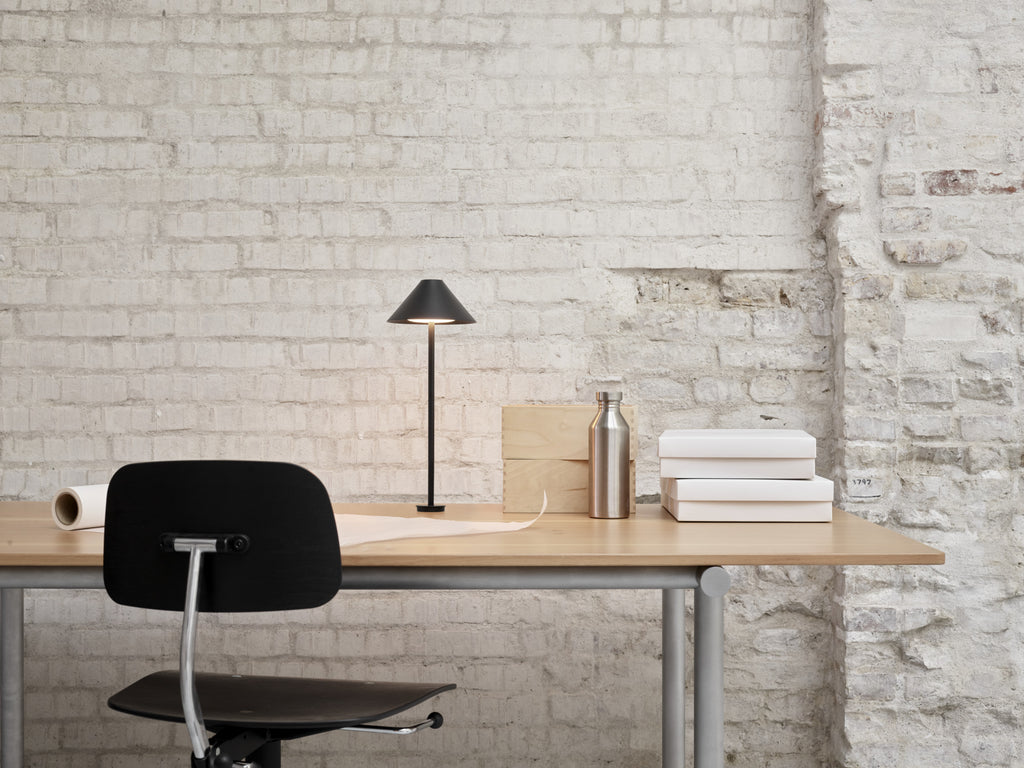 The Keglen table lamp’s distinctive conical shade has a built-in curved diffuser. This ensures an attractive and glare-free downwardly directed light. The stem morphs into the diffuser shade, folding inward and creating a beautiful organic geometry. A gentle light is also emitted upward through a discreet uniform opening in the top of the shade to create a perfect ambiance. Designed by Jakob Lange.