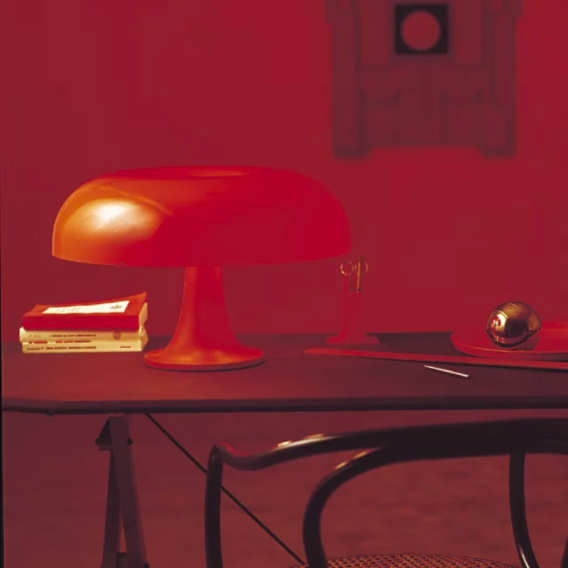 The Nesso Table Lamp from Artemide in orange in a living room.
